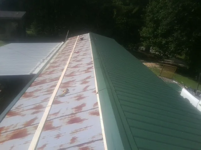 Old rusted panels beside newly installed green metal roofing — Wind Damage Roof Repair by Roofing Brothers in Fruitvale