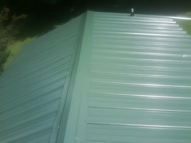 New green metal panels meeting at the ridge of a roof — Flat Roof Repair work by our crew in Fruitvale
