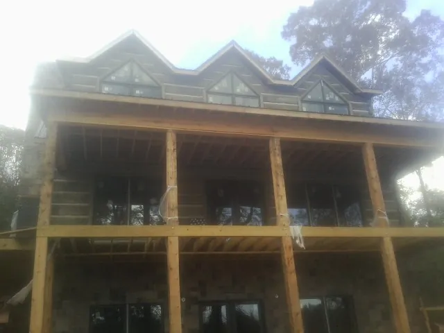 Dormers and porch framing on a large log home under construction — Roof Coating work by our crew in Fruitvale