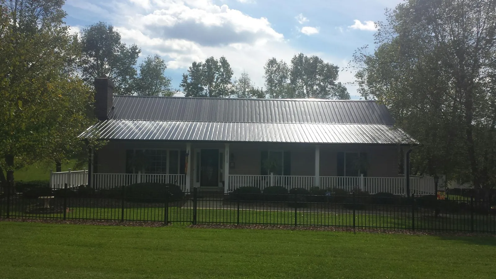 Gray metal roof on a brick ranch with a full width front porch — Gutter Guard Installation work by our crew in Fruitvale