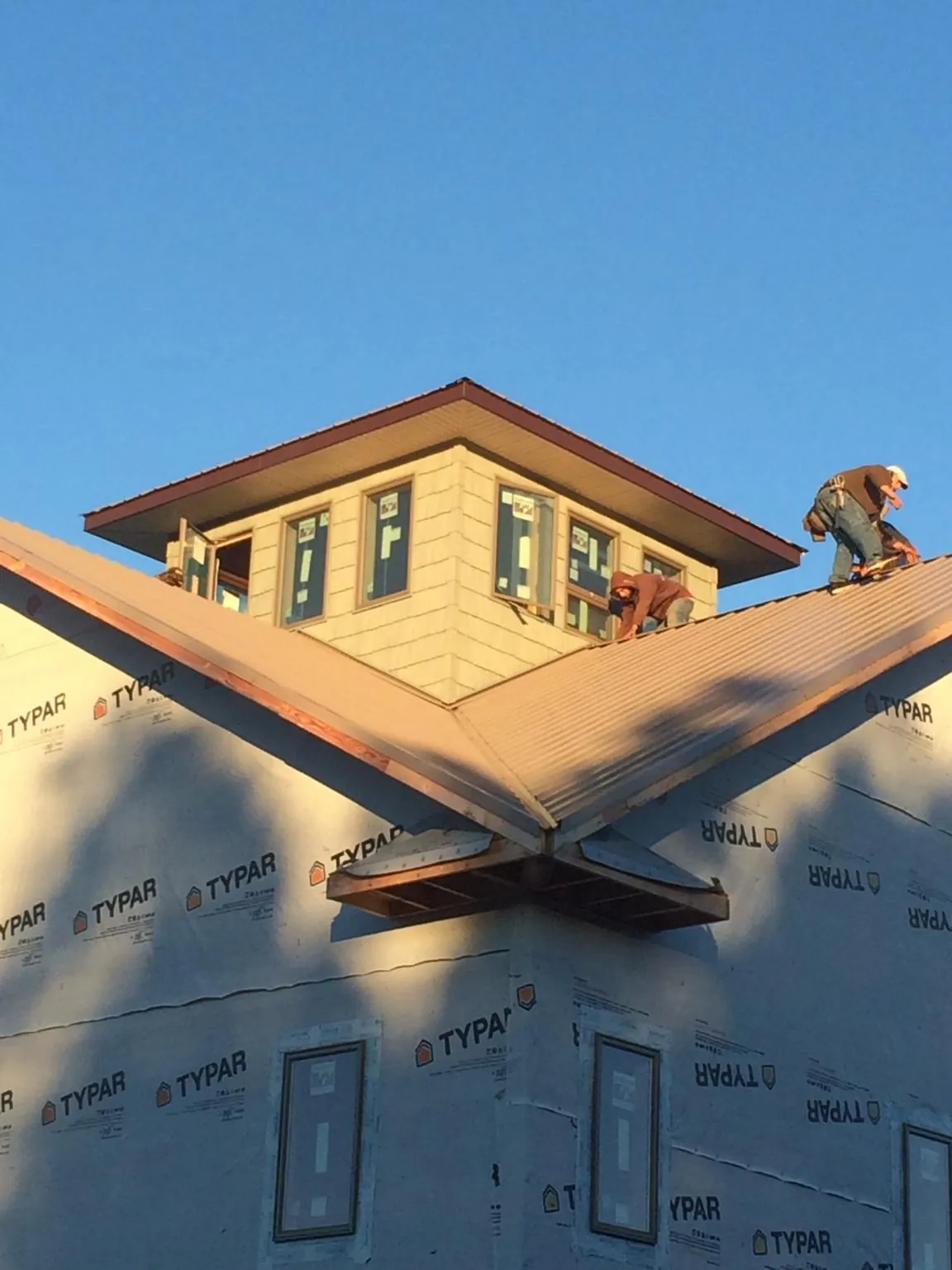 Roofers working around a rooftop cupola on a new metal roof at sunset — Roof Waterproofing in Fruitvale by Roofing Brothers
